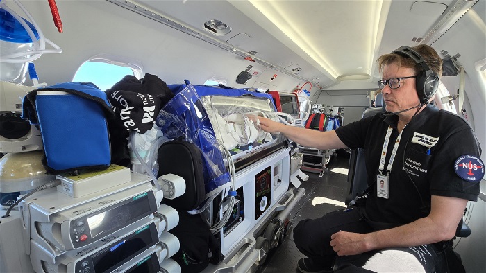 Sjuksköterska arbetar vi transportkuvös i ambulansflyg