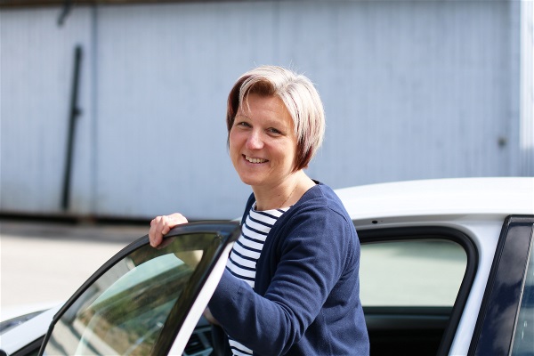 Bild på Magdalena Mörtzell, arbetsterapeut, vid en bil utomhus.