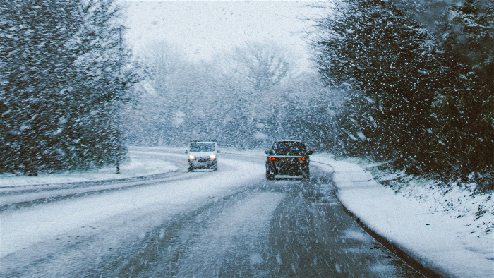 Två bilar som möts på vägen när det snöar.