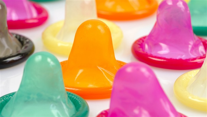 Kondomer på ett bord i olika färger. Foto.